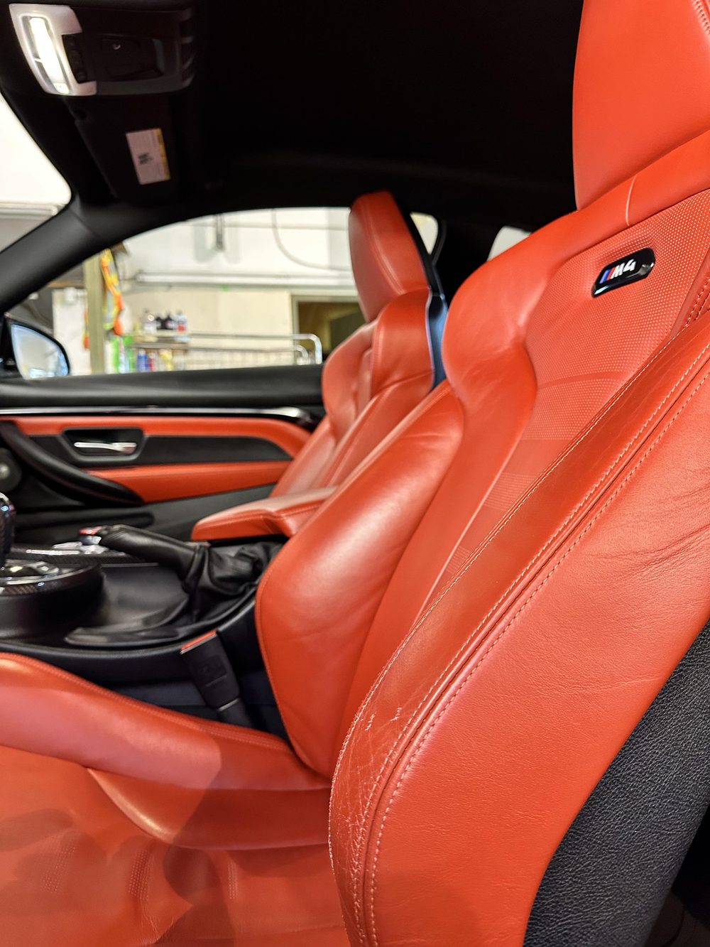 Freshly cleaned and conditioned red leather sport seats in a BMW M4 inside the shop